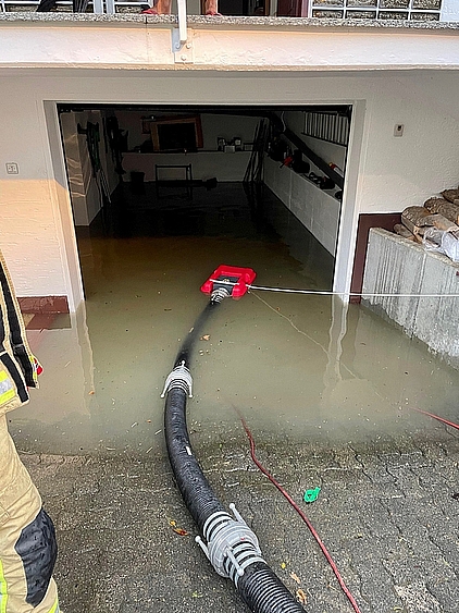 Garage mit Wasser voll gelaufen und Saugschläuchen, die Wasser abpumpen