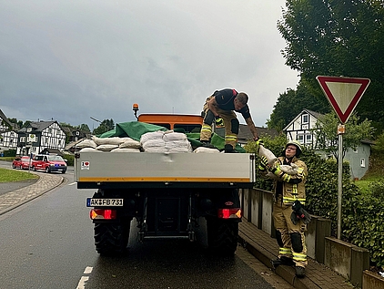 Sandsäcke werden von Feuerwehrleuten von einem Unimog abgeladen